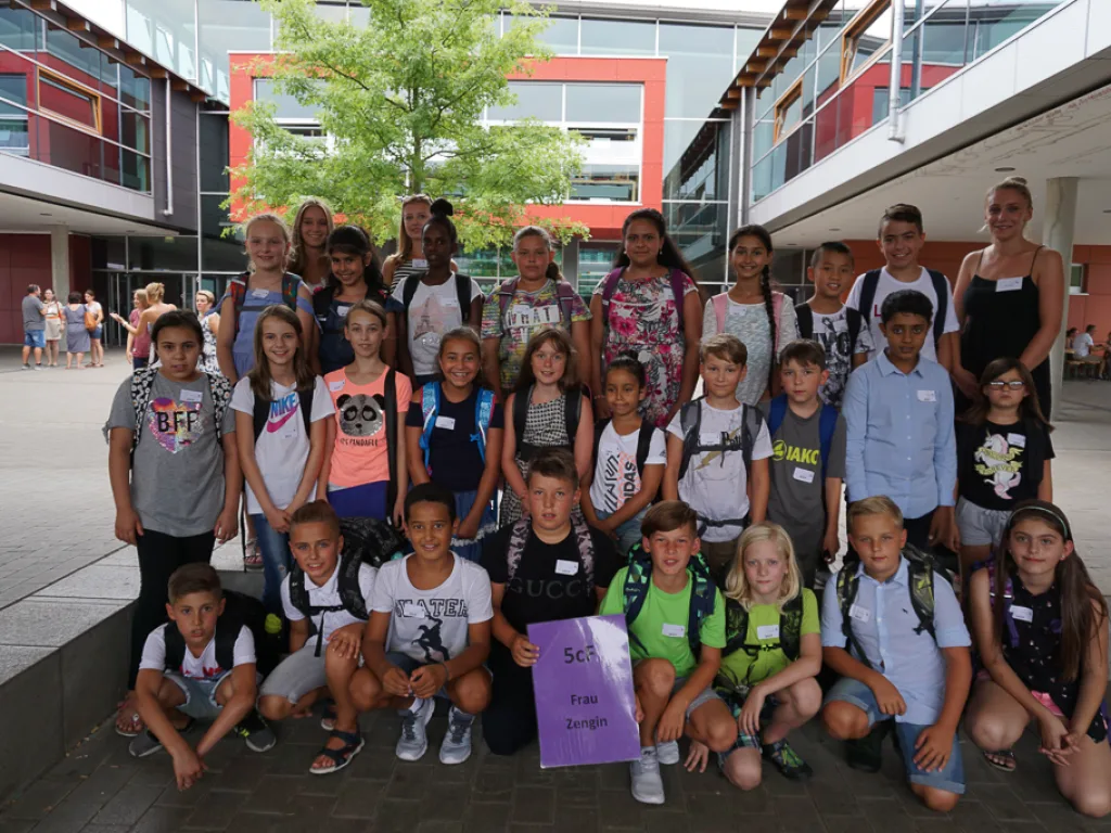 Klassenfoto einer neuen fünften Klasse mit lila Schild.
